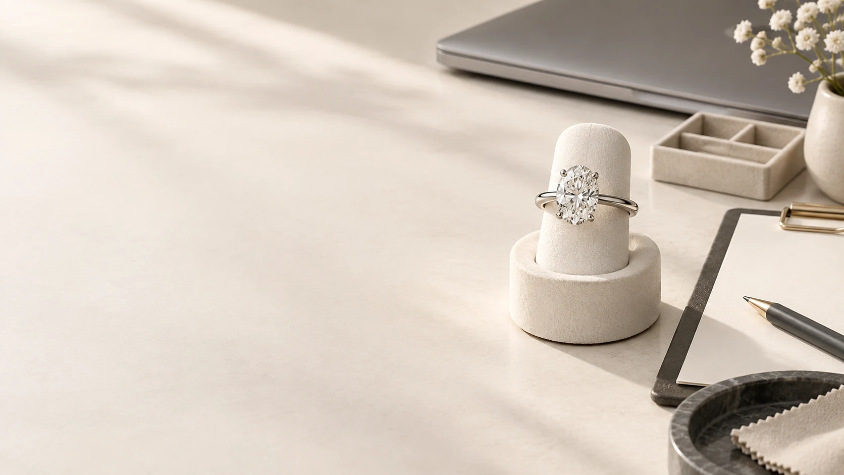 Oval solitaire engagement ring beside a laptop and launch planning clipboard.
