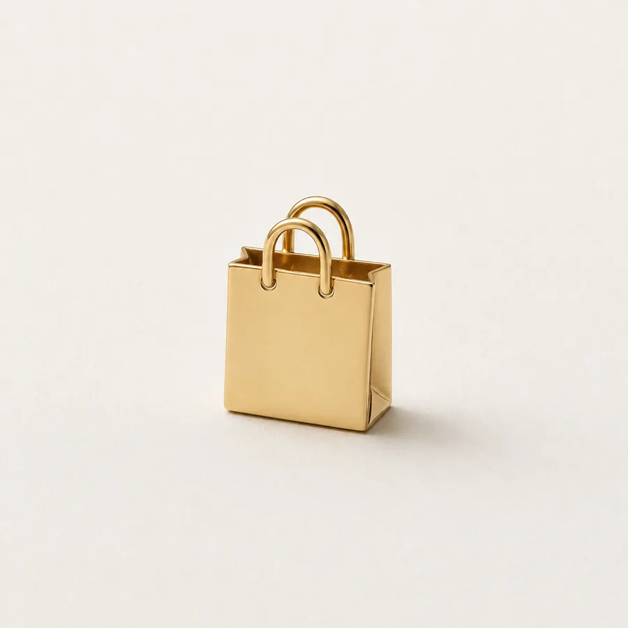 A small shopping bag sculpted in polished gold, standing on off-white paper